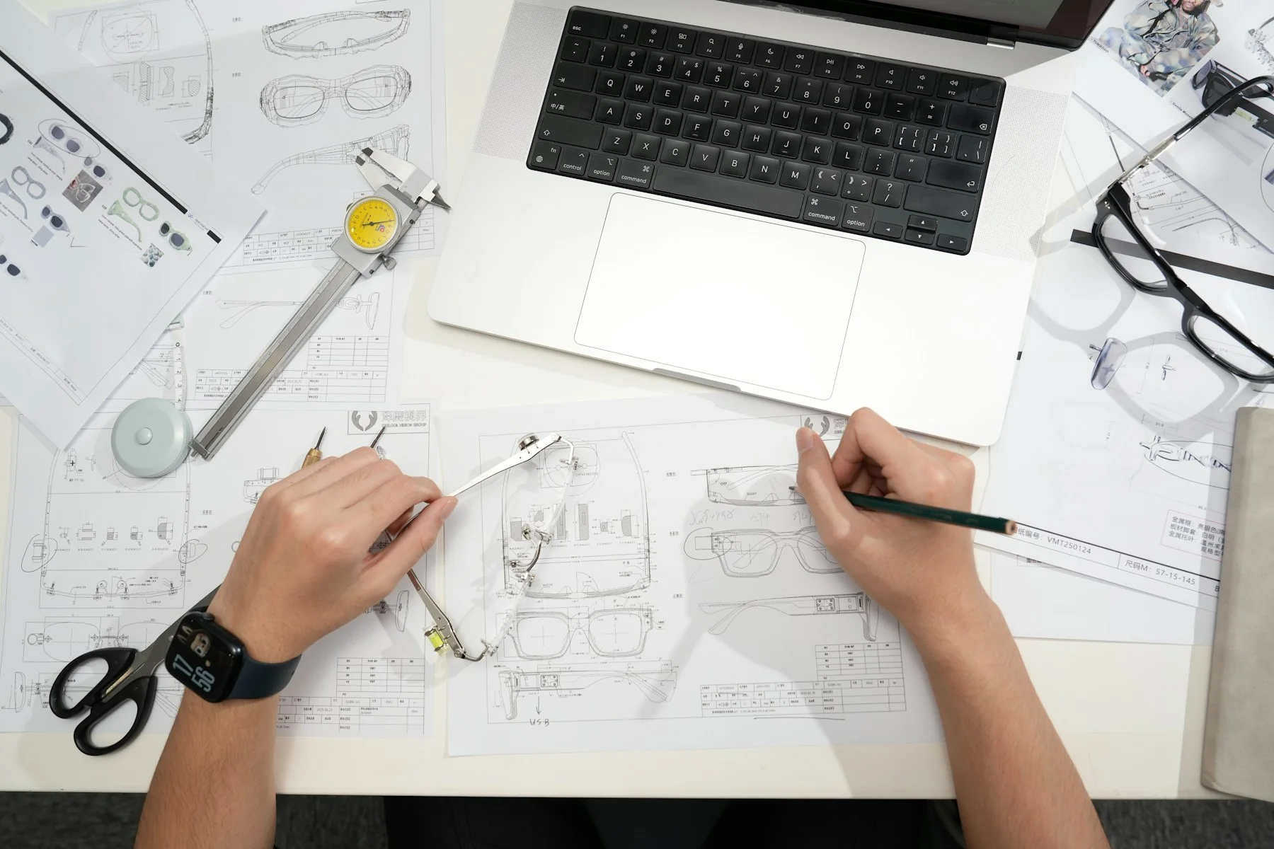 A designer developing a drawing beside a laptop